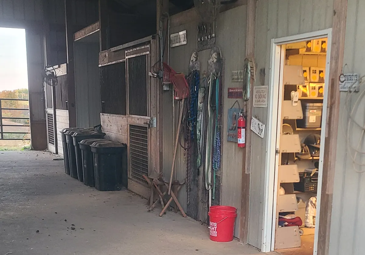 Inside the main barn: stalls along the aisle and the tack room door